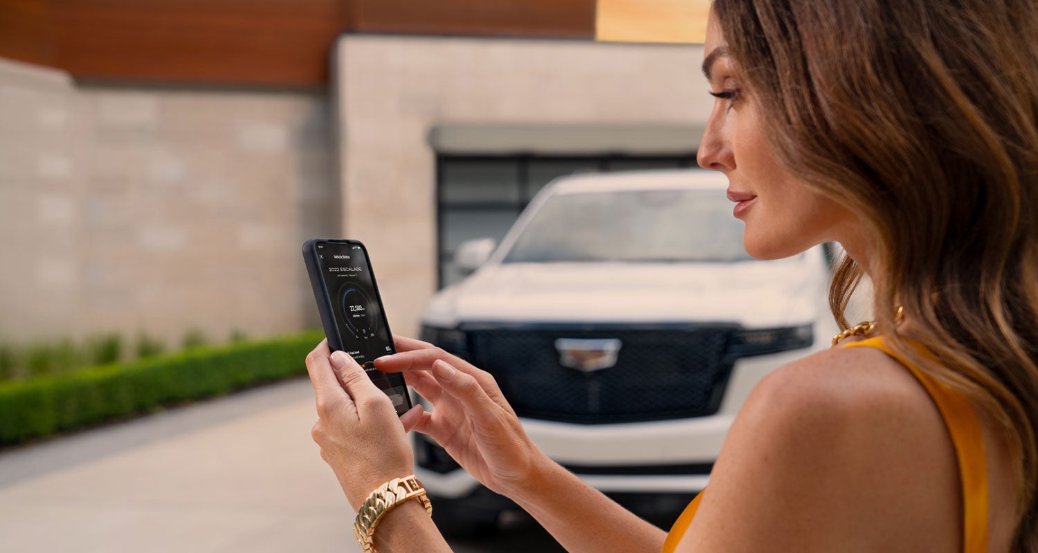 lady checking her mobile with a Cadillac vehicle background | D'Addario Cadillac in Shelton CT